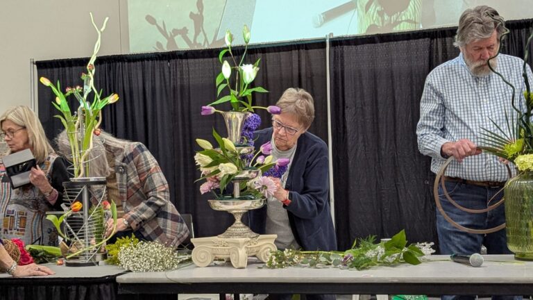 three people creating flower sculptures
